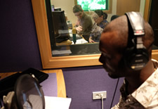 Booth at PrimeVoices’ studio 1 with male voice talent reading a script